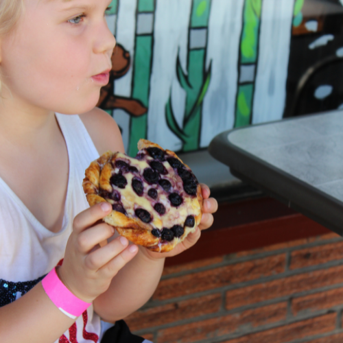Pink children's wristband on wrist holding pastry from Ovenbird Bakery