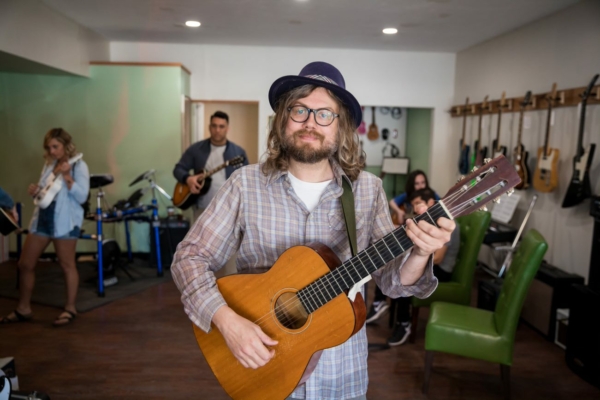 Shows owner of Musical Independence with guitar in hand inside of store
