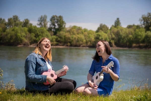 Shows two people playing ukuleles by the river in Independence, Oregon
