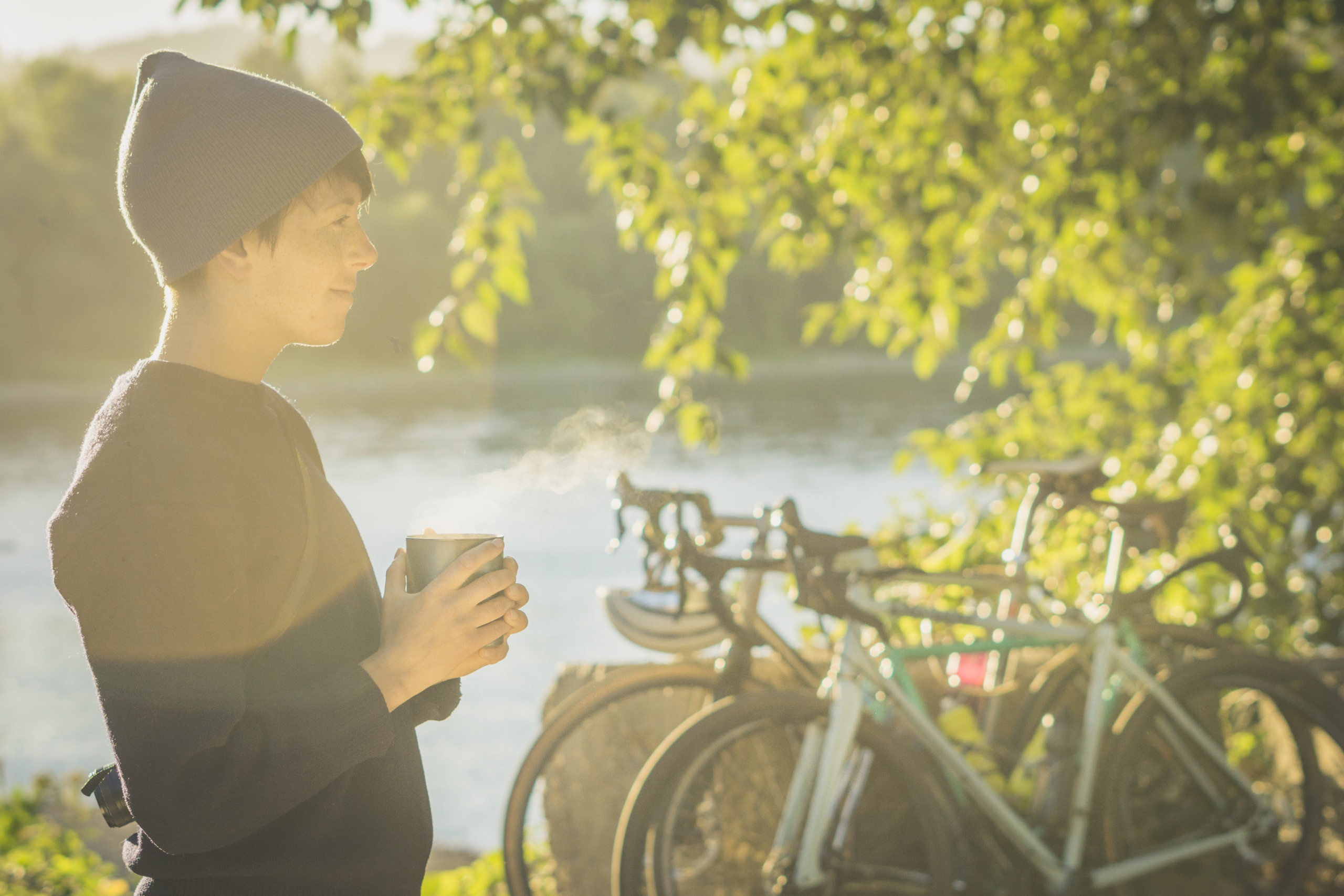 Woman in the morning sun with bikes and river in the background